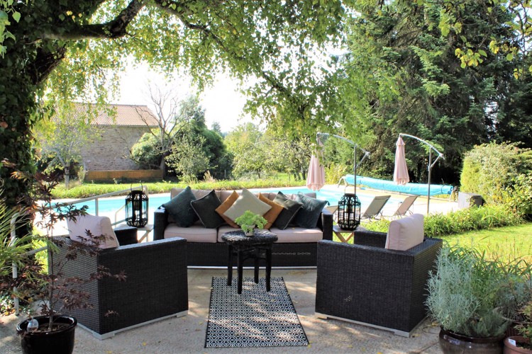 Dark brown hessian settee and two matching chairs with cushions on a patio with a pool behinde chairstraw B