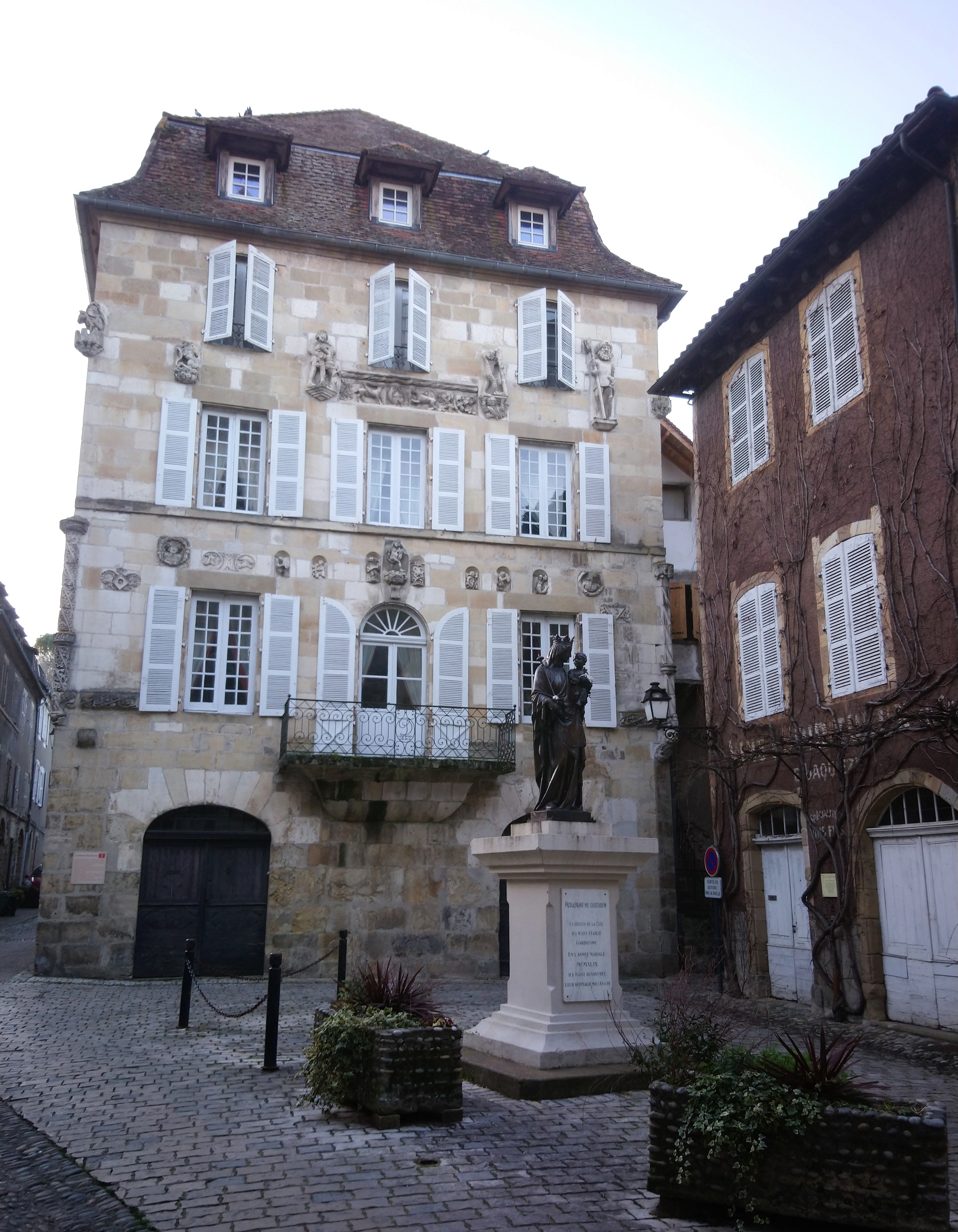Beaulieu sur Dordogne Beaulieu sur Dordogne old shuttered 5 story house with madonna statue outside on standp