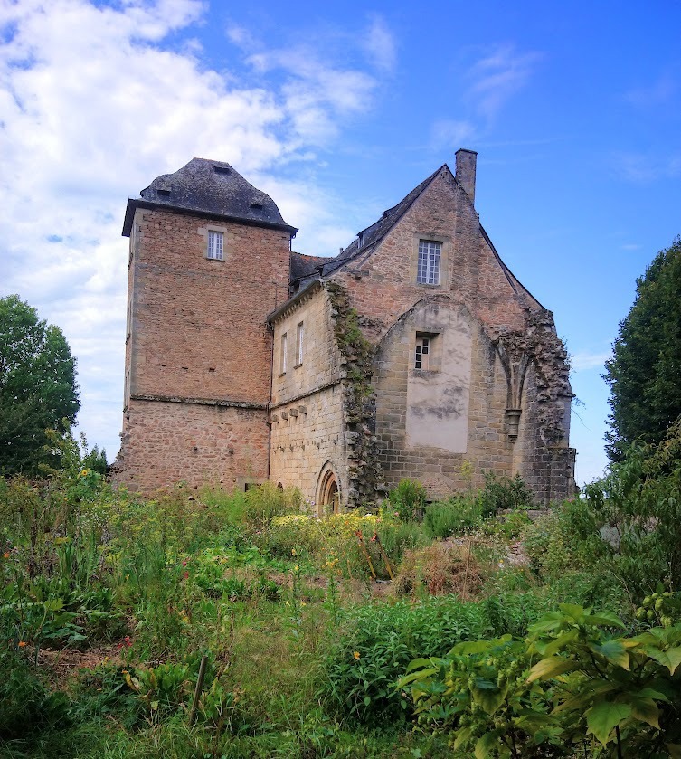 Aubazine Abbey Red brick abbey with triangle roof and garden in front