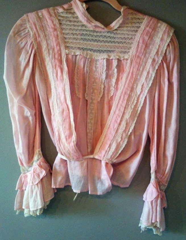 A pale pink high necked Victorian long sleeved blouse dripping with luscious delicate white lace