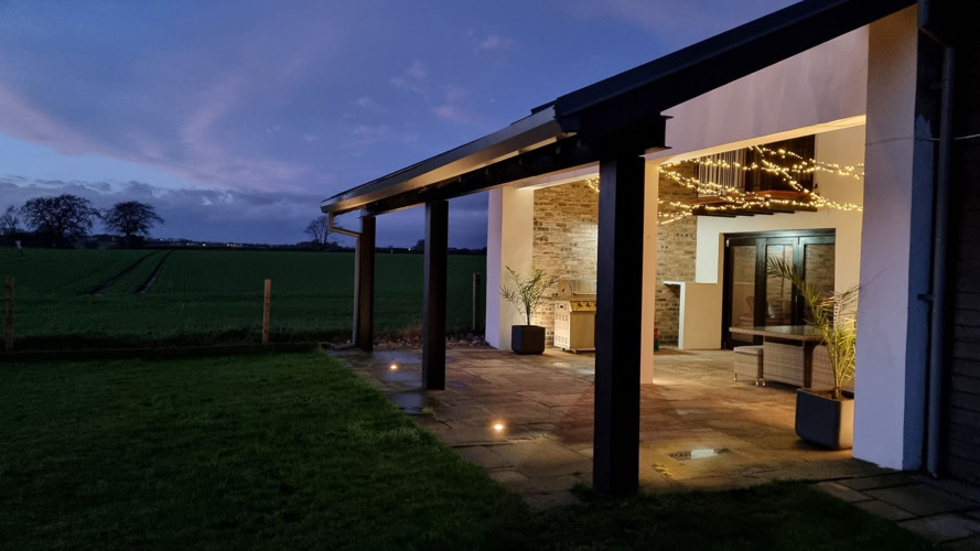 outdoor sheltered and glass roofed terrace with lights on at night
