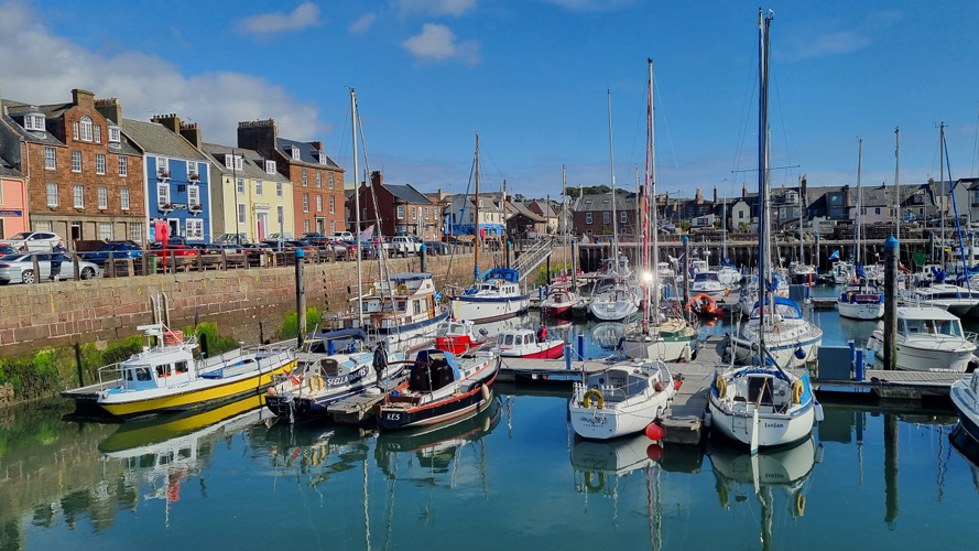 Arbroath harbour with colourful boats and fishing boats in the harbour with different coloured houses