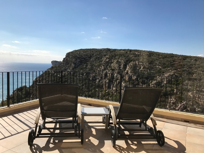 Two sun loungers on the terrace facing the sea and mountains, blue sky
