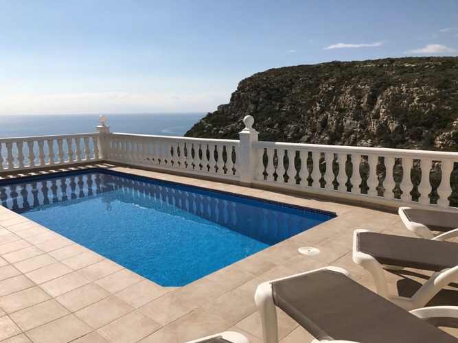 Across the pool terrace with sun loungers, looking out to sea