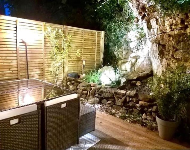 Image of lower fully decked garden with seating and table at night , at Moulton View Holiday Cottage