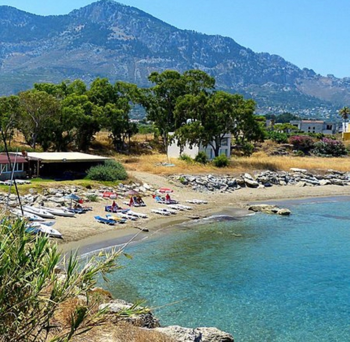 Sandy cove with sun loungers and a mountain backdrop on the Lapta coast